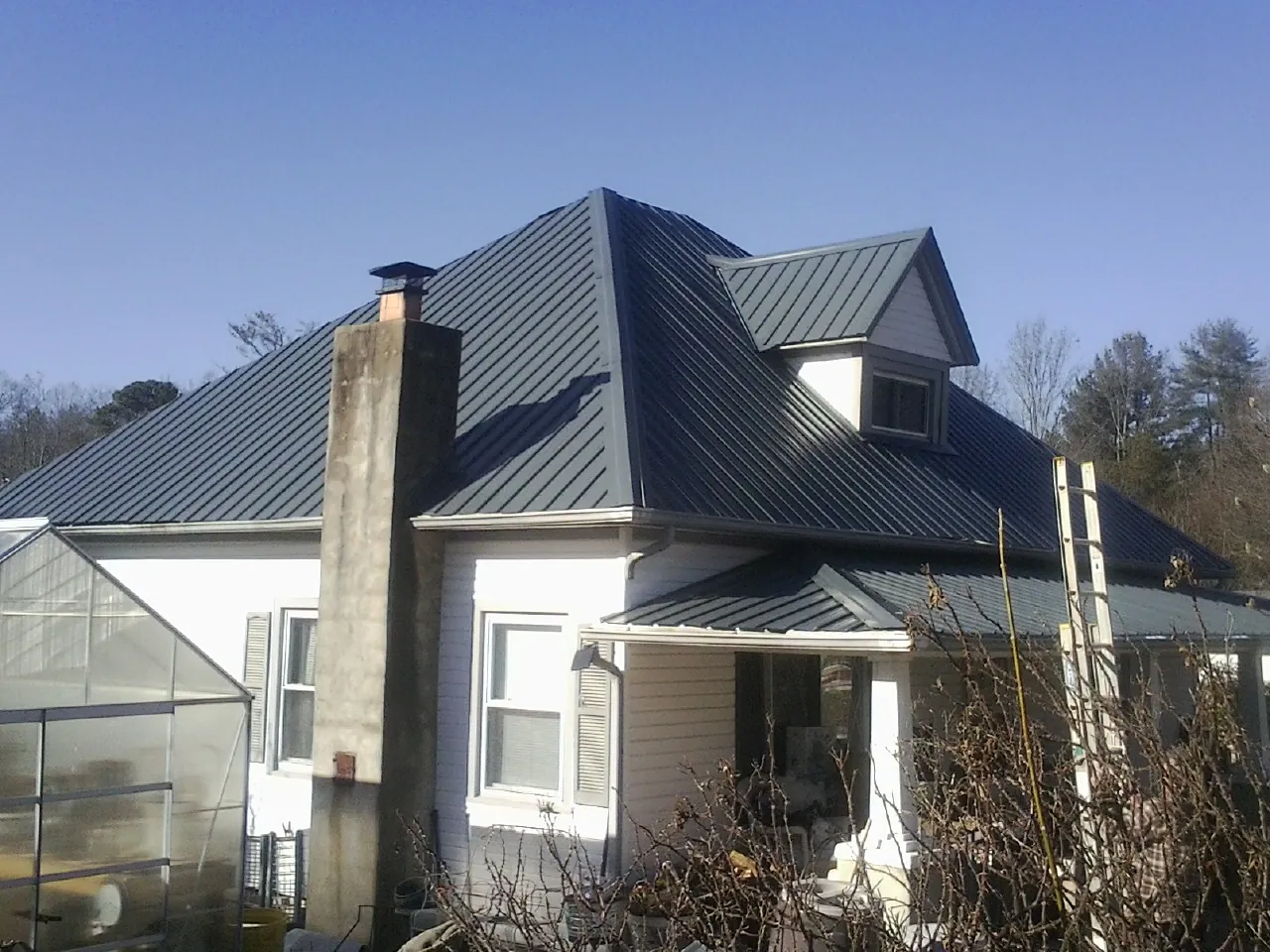 Dark blue standing seam metal roof on a white farmhouse with dormer — Slate & Tile Roof Repair by Roofing Brothers in Sublimity