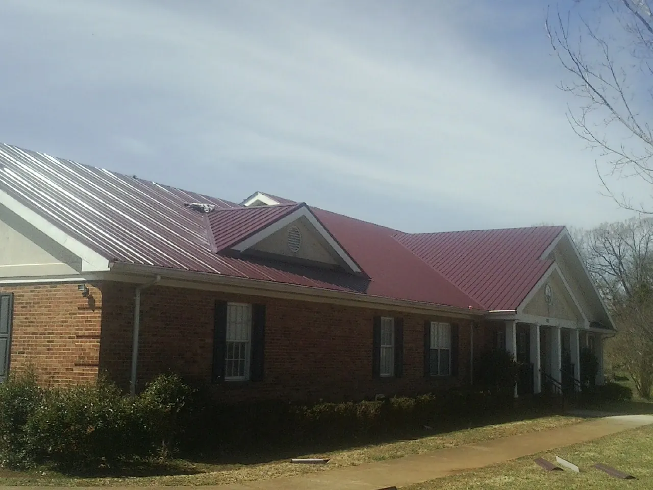 Red metal roof with gabled entries on a long brick building in Sublimity