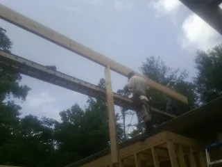 Carpenter setting a ridge beam over a new addition frame — Ice Dam Removal by Roofing Brothers in Sublimity
