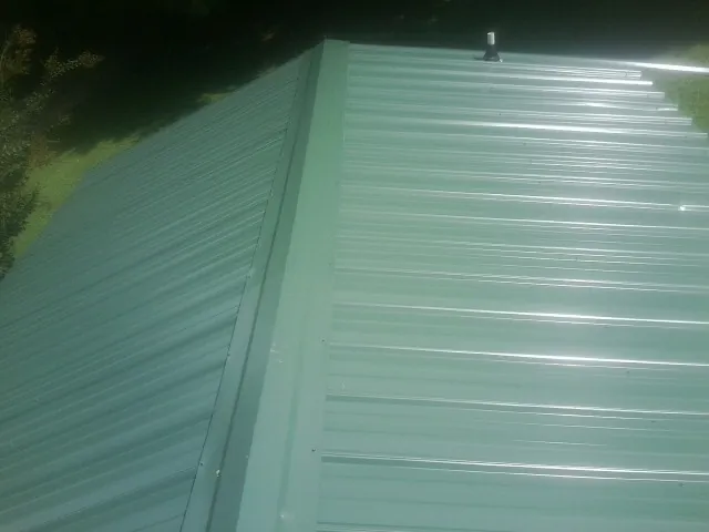 New green metal panels meeting at the ridge of a roof — Flat Roof Repair work by our crew in Sublimity