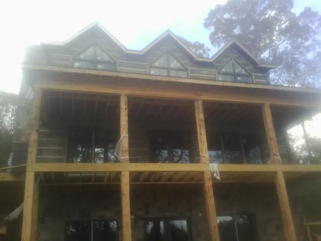 Dormers and porch framing on a large log home under construction — Roof Coating work by our crew in Sublimity