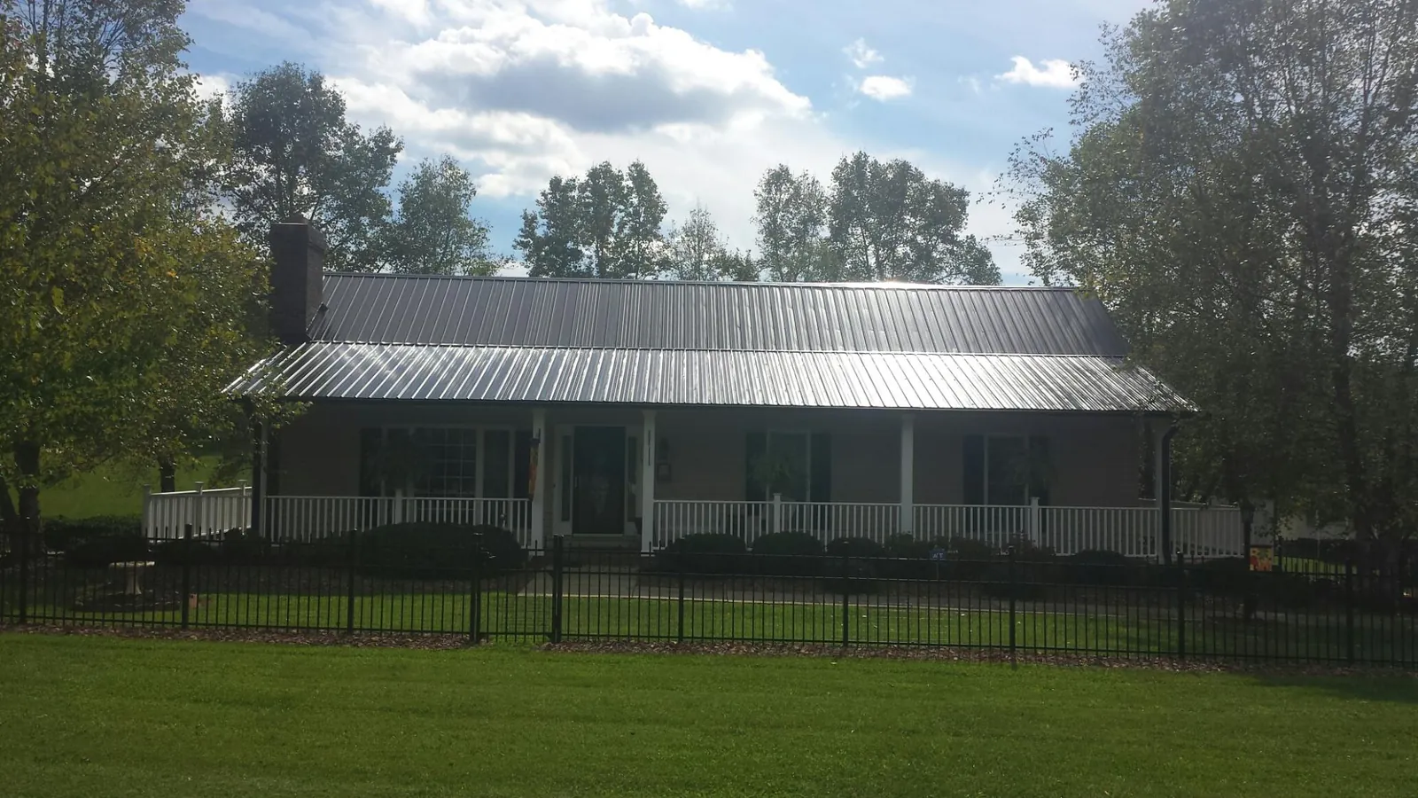 Gray metal roof on a brick ranch with a full width front porch — Gutter Guard Installation work by our crew in Sublimity