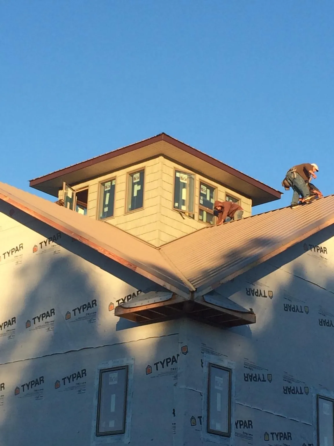 Roofers working around a rooftop cupola on a new metal roof at sunset — Roof Waterproofing in Sublimity by Roofing Brothers